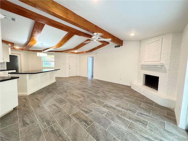 unfurnished living room featuring beamed ceiling, a brick fireplace, and ceiling fan