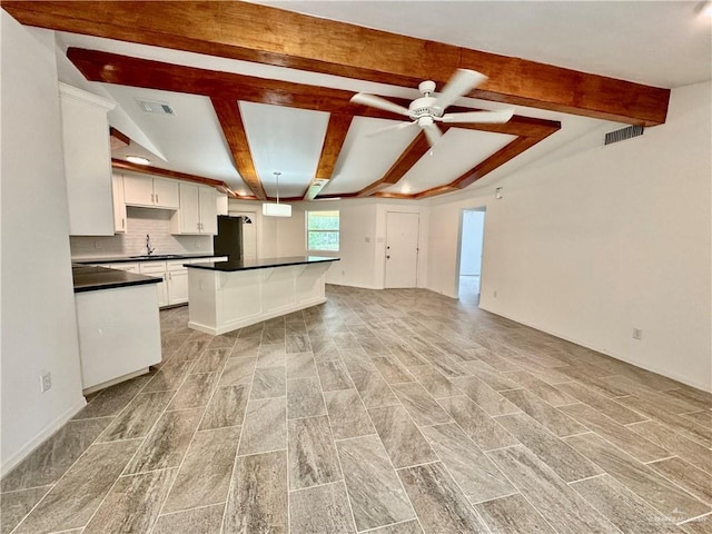 kitchen featuring light wood-type flooring, tasteful backsplash, sink, white cabinets, and a center island