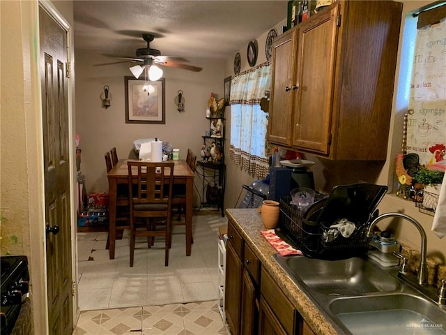 kitchen with light tile patterned floors, black range with electric cooktop, ceiling fan, and sink