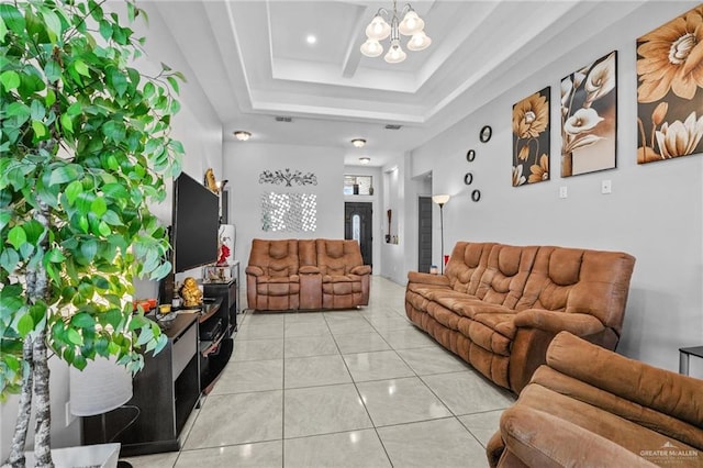 living room with a notable chandelier, light tile patterned floors, and a tray ceiling