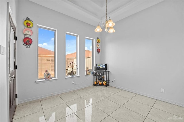 tiled spare room featuring an inviting chandelier