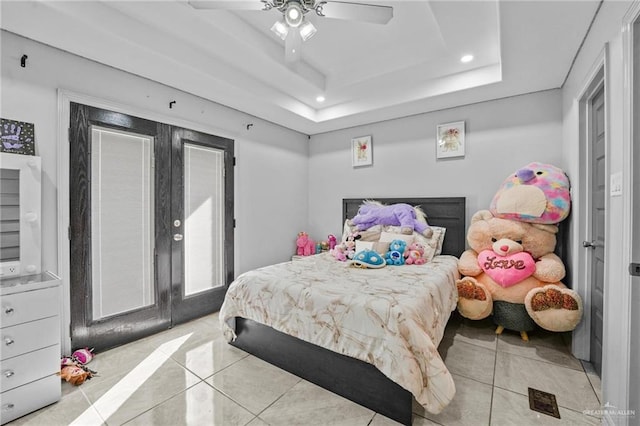 bedroom featuring ceiling fan, light tile patterned floors, french doors, and a tray ceiling