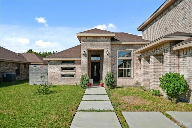 view of exterior entry featuring a lawn and central AC unit