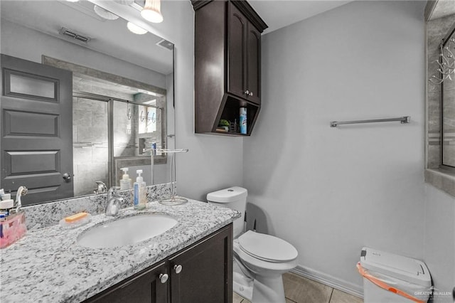 bathroom featuring tile patterned flooring, vanity, toilet, and a shower with door