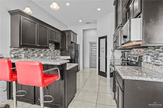 kitchen with a kitchen bar, backsplash, stainless steel appliances, and decorative light fixtures