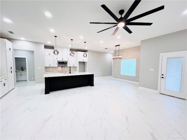 kitchen featuring white cabinets, an island with sink, and decorative light fixtures