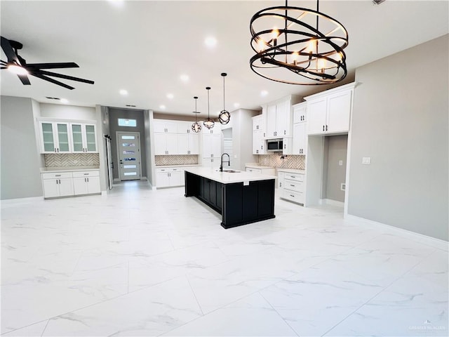 kitchen with tasteful backsplash, a kitchen island with sink, sink, and pendant lighting