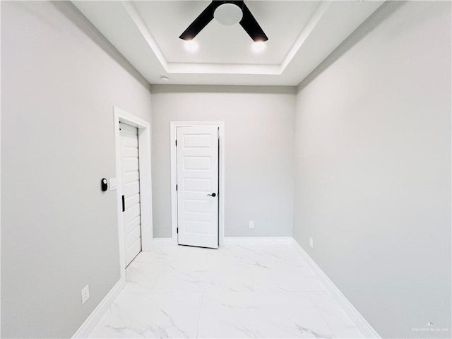 unfurnished room with ceiling fan and a tray ceiling