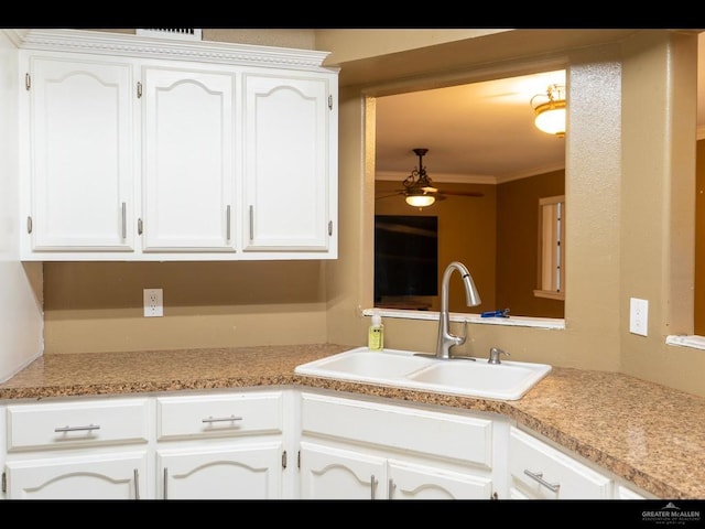 kitchen featuring white cabinets, ceiling fan, crown molding, and sink