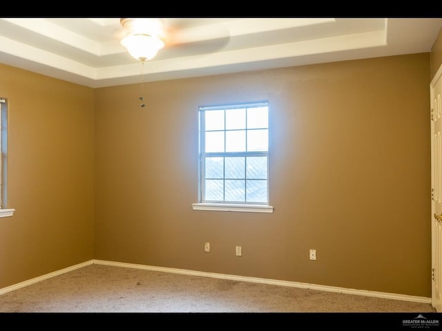 spare room featuring carpet, a raised ceiling, and ceiling fan