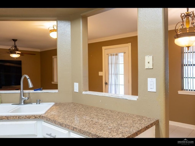 kitchen featuring crown molding, sink, white cabinets, and light tile patterned floors