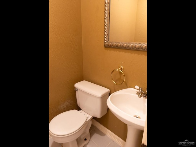 bathroom featuring toilet, tile patterned floors, and sink