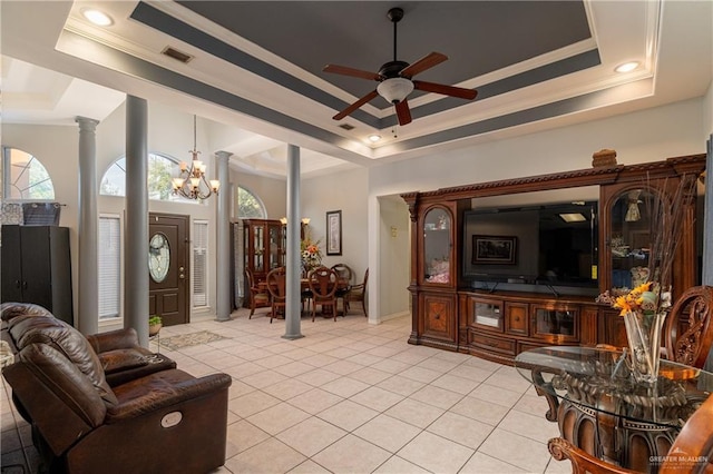 tiled living room featuring decorative columns, crown molding, ceiling fan with notable chandelier, and a tray ceiling