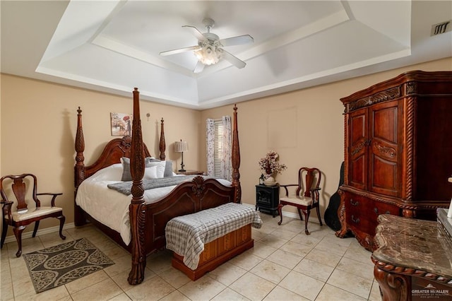 tiled bedroom with ceiling fan and a tray ceiling