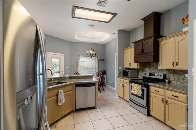 kitchen with sink, light tile patterned floors, appliances with stainless steel finishes, a tray ceiling, and a chandelier