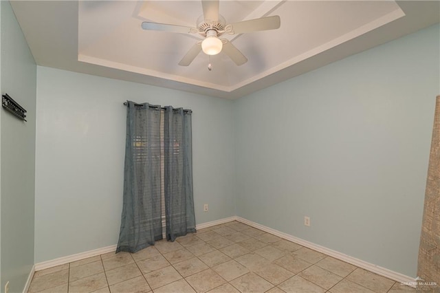 tiled empty room with a raised ceiling and ceiling fan