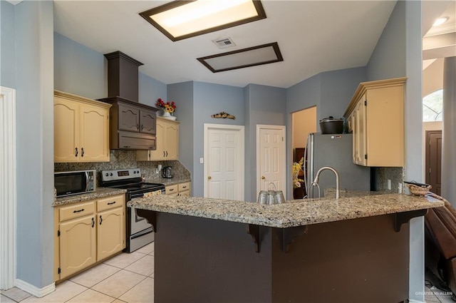 kitchen with appliances with stainless steel finishes, decorative backsplash, a kitchen bar, and kitchen peninsula