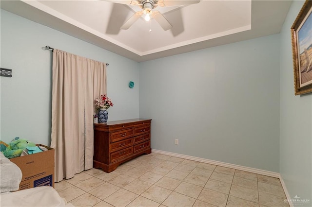 bedroom featuring ceiling fan, a tray ceiling, and light tile patterned floors