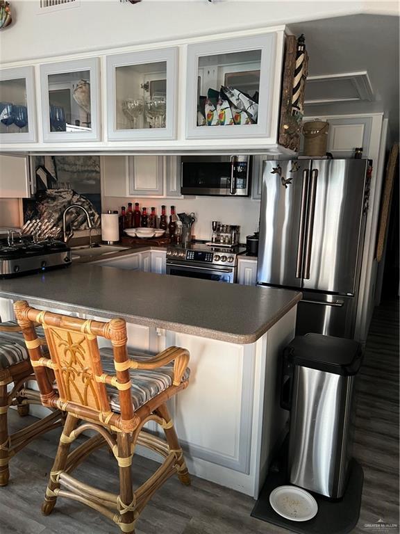 bar featuring visible vents, dark wood-style floors, indoor wet bar, stainless steel appliances, and a sink