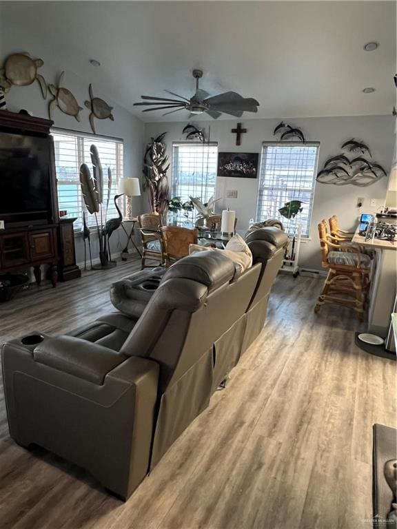 living area with ceiling fan, plenty of natural light, vaulted ceiling, and wood finished floors