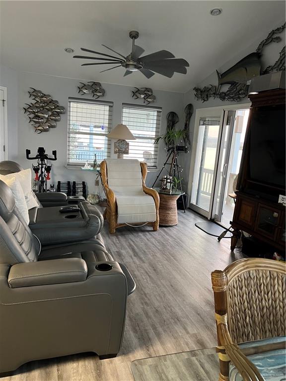 living area with a ceiling fan, lofted ceiling, and light wood finished floors