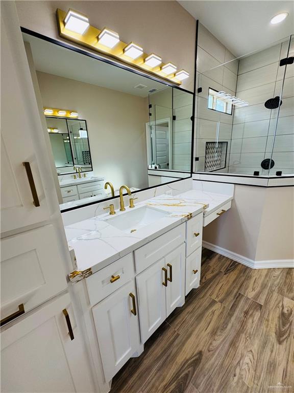 bathroom featuring hardwood / wood-style flooring, vanity, and an enclosed shower