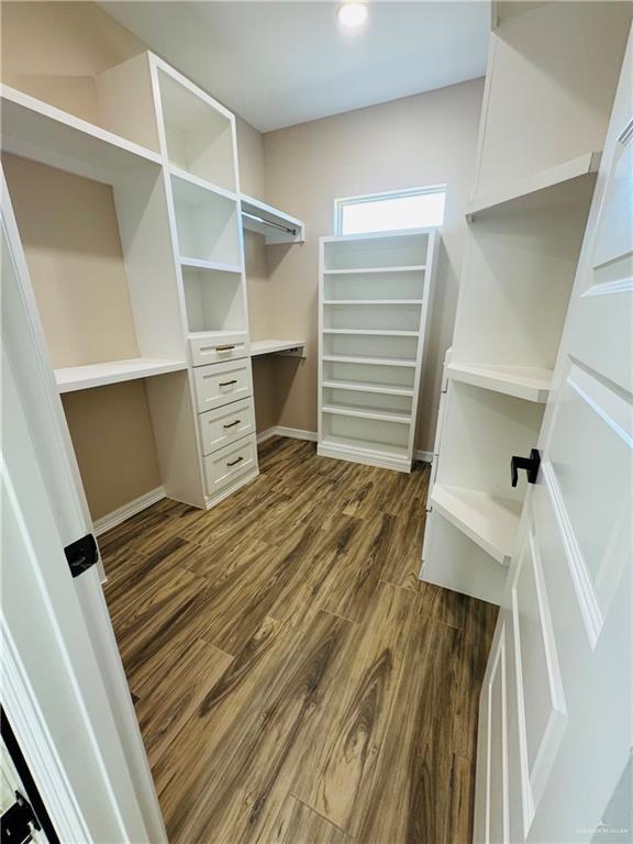 walk in closet with dark hardwood / wood-style flooring