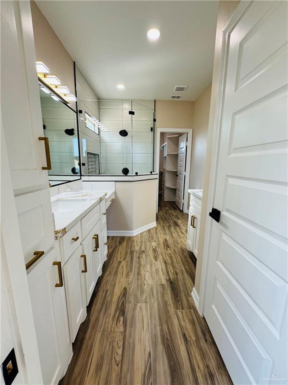 bathroom featuring wood-type flooring, vanity, and a shower with shower door