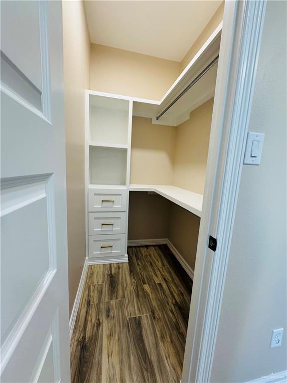 walk in closet with dark wood-type flooring and built in desk