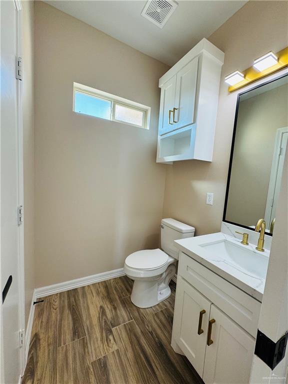 bathroom with wood-type flooring, vanity, and toilet