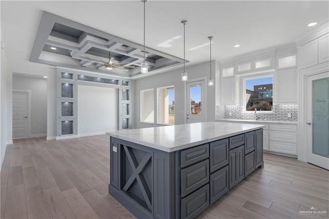 kitchen with ceiling fan, backsplash, a center island, coffered ceiling, and white cabinetry