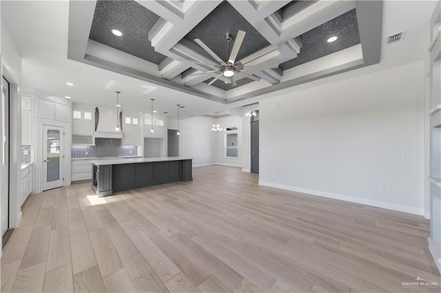 kitchen featuring pendant lighting, a large island with sink, white cabinets, tasteful backsplash, and coffered ceiling