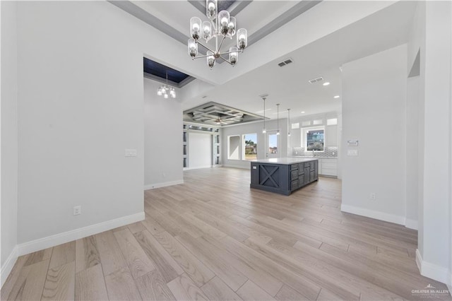 kitchen with hanging light fixtures, light hardwood / wood-style flooring, an inviting chandelier, and a kitchen island