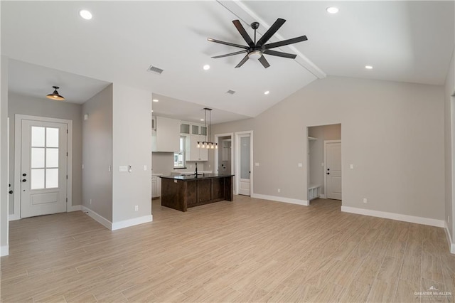 unfurnished living room featuring lofted ceiling with beams, baseboards, light wood-type flooring, and ceiling fan