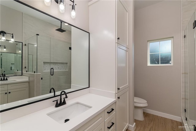 bathroom with a stall shower, wood finished floors, two vanities, and a sink