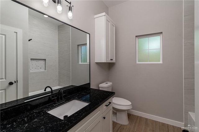 bathroom with toilet, vanity, baseboards, and wood finished floors