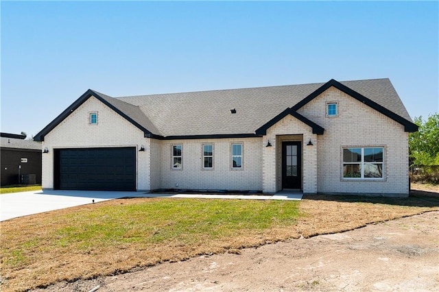 view of front of property with brick siding, driveway, an attached garage, and a front lawn