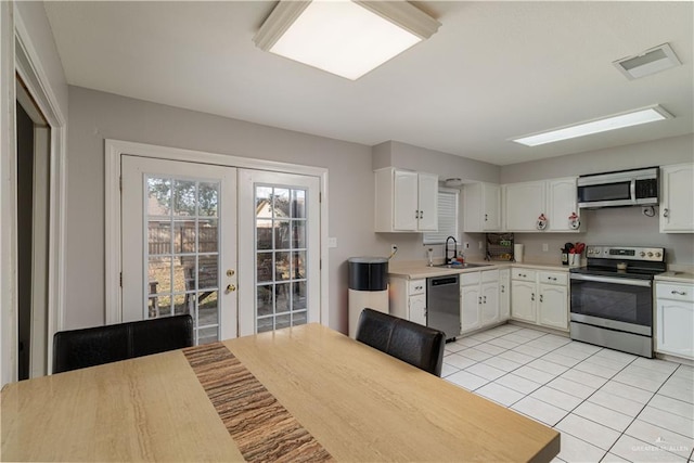 kitchen with sink, white cabinets, light tile patterned flooring, and appliances with stainless steel finishes