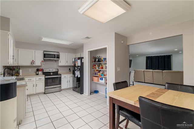 kitchen with sink, white cabinets, light tile patterned floors, and appliances with stainless steel finishes