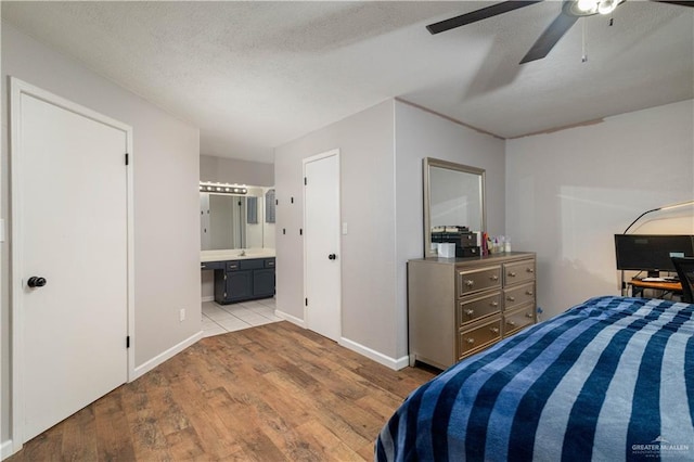 bedroom with ensuite bath, ceiling fan, a textured ceiling, and light wood-type flooring