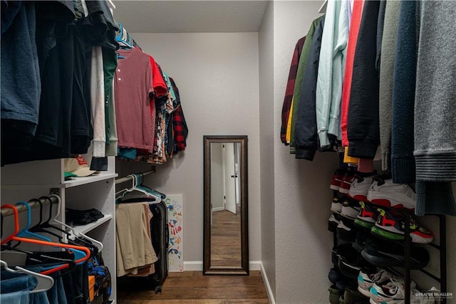 walk in closet with dark wood-type flooring