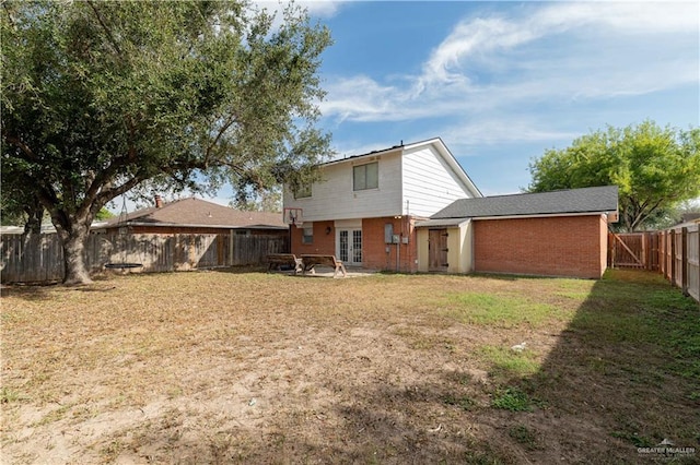 rear view of house with a lawn and french doors