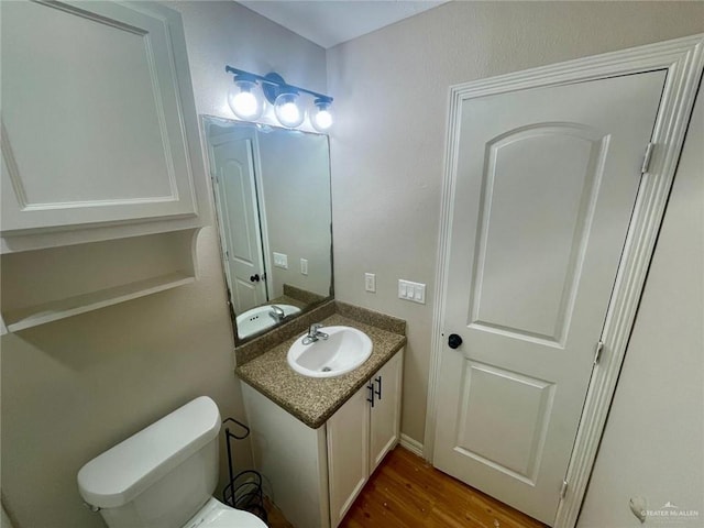 bathroom featuring wood-type flooring, vanity, and toilet