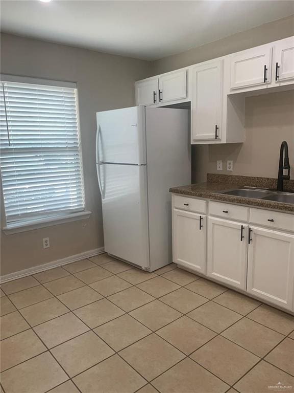 kitchen featuring white cabinets, white fridge, light tile patterned floors, and sink