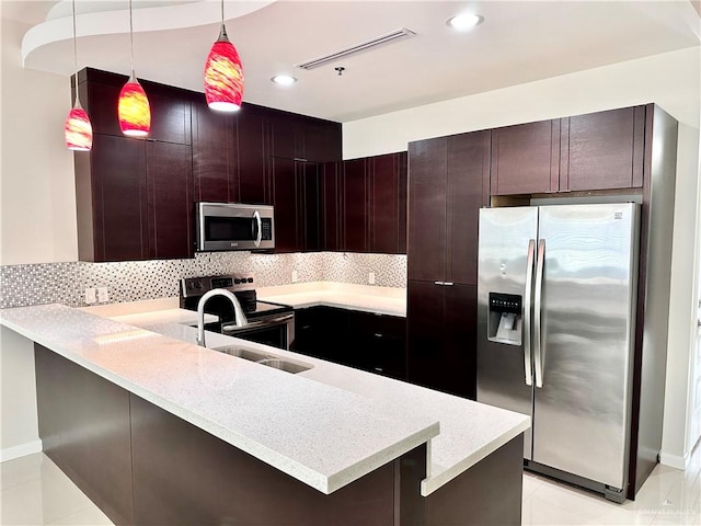 kitchen featuring kitchen peninsula, appliances with stainless steel finishes, a kitchen breakfast bar, tasteful backsplash, and pendant lighting