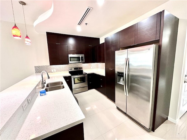 kitchen featuring dark brown cabinetry, sink, hanging light fixtures, decorative backsplash, and appliances with stainless steel finishes