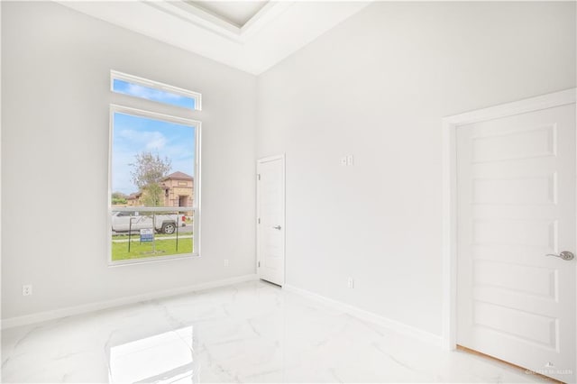 unfurnished room featuring marble finish floor and baseboards