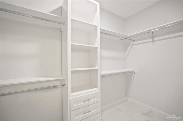 walk in closet featuring marble finish floor