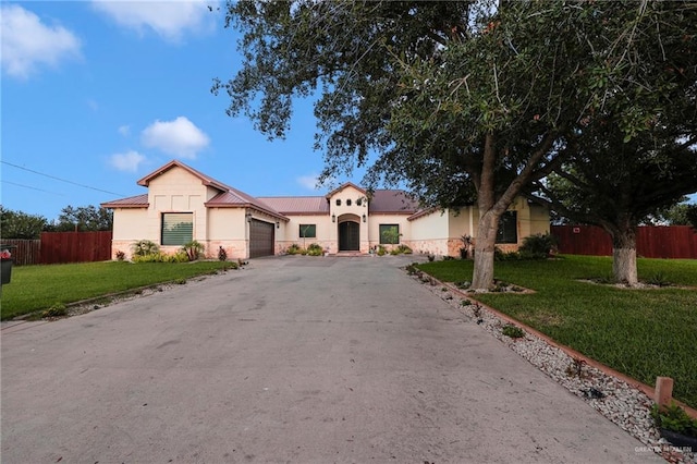 1320 S Cesar Chavez Rd, Edinburg, TX 78542 - mediterranean / spanish home with an attached garage, stone siding, asphalt driveway, stucco siding, and a standing seam roof