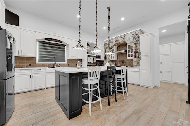 1320 S Cesar Chavez Rd, Edinburg, TX 78542 - kitchen featuring refrigerator with ice dispenser, a kitchen island, backsplash, white cabinetry, and light countertops